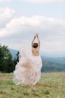 whirling bride holding veil skirt of wedding dress at pine forest photo