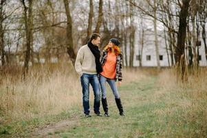 Young couple walks in autumn forest. Man giving his girlfriend piggyback. People having fun outdoors photo