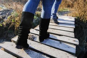 person in boots with jeans on the green grass near the snow spring is coming photo
