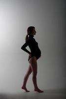 Young beautiful pregnant woman in black bodysuit and hat. photo