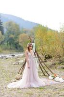 novia feliz con un vestido de novia rosa. la chica tiene un ramo de novia en sus manos. ceremonia de boda estilo boho en el bosque.