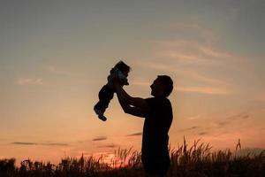 A father throws up his little daughter at sunset. photo