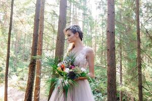 novia feliz con un vestido de novia rosa. la chica tiene un ramo de novia en sus manos. ceremonia de boda estilo boho en el bosque. foto