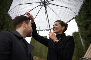 Young beautiful loving Hispanic couple walks under an umbrella during the rain. photo