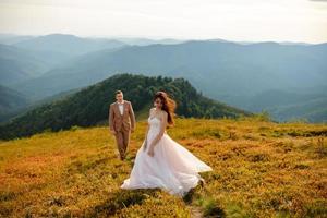 pareja de bodas enamorada besándose y abrazándose cerca de rocas en un hermoso paisaje foto