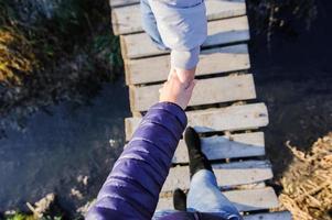 persona con botas con jeans en la hierba verde cerca de la nieve se acerca la primavera foto