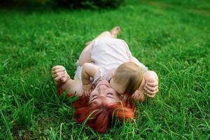 Mom hugs and plays with her one-year-old daughter wrapped in a towel after bathing. photo