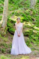 Happy bride in a pink wedding dress. The girl holds a wedding bouquet in her hands. Boho style wedding ceremony in the forest. photo