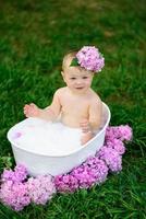 Little girl bathes in a milk bath in the park. The girl is having fun in the summer. photo