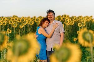 Adult farmer and wife spend time in the field. The man is sitting. A woman stands next to him and hugs him. A woman kisses her husband on the head. photo