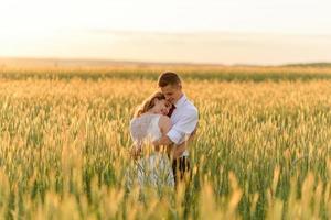 Bride and groom in a wheat field. The couple hugs during sunset