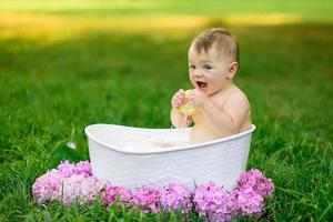 Little girl bathes in a milk bath in the park. The girl is having fun in the summer.