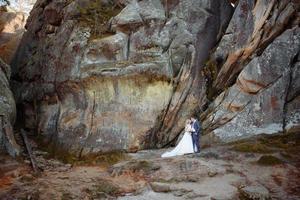 The bride and groom are standing on top of a cliff. Sunset. photo