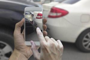 mano sosteniendo un teléfono inteligente, tome una foto en la escena de un accidente automovilístico, accidente automovilístico para el seguro