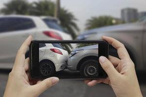 mano sosteniendo un teléfono inteligente, tome una foto en la escena de un accidente automovilístico, accidente automovilístico para el seguro