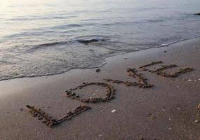 playa agua de mar en la playa escrita en arena, amor foto