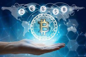 mano que sostiene la red global usando la interfaz de símbolo de signo de moneda de bitcoin fintech, concepto de tecnología blockchain de moneda virtual, concepto de tecnología financiera de inversión. foto