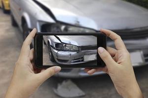 mano sosteniendo un teléfono inteligente, tome una foto en la escena de un accidente automovilístico, accidente automovilístico para el seguro