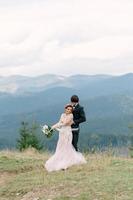 Stylish young bride and groom stand in boat on background cloude sky sea and mountains of Montenegro photo