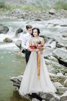 la novia y el novio. ceremonia de boda cerca de un río de montaña foto