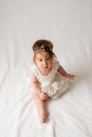 niña de 6 meses con un peine en la mano sobre un fondo blanco. foto