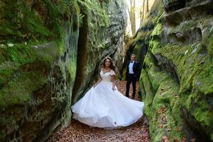 Bride and groom. A couple strolling among the narrow beautiful gorge. The gorge was overgrown with green moss. The newlyweds are spinning and running.