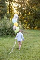 un niño en edad escolar primaria corre con globos. el niño celebra su cumpleaños en el parque. foto