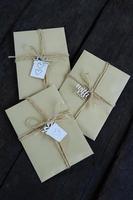 Brown kraft envelopes tied with an old tourniquet on old wood background with copy space. Handmade gift wrap. photo