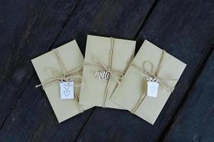 Brown kraft envelopes tied with an old tourniquet on old wood background with copy space. Handmade gift wrap. photo