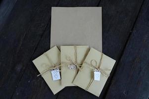 Brown kraft envelopes tied with an old tourniquet on old wood background with copy space. Handmade gift wrap. photo