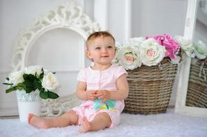 The little one-year-old girl smiles and sits. photo