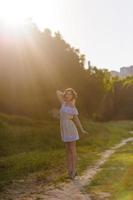 Portrait of a young beautiful girl in a sundress. Summer photo session in the park at sunset. A girl sits under a tree in the shade.