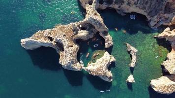 Aerial drone shot of kayaks and boats passing around magical Ponta da Piedade limestone cliffs. Exploring caves and tunnels of Lagos, Algarve, South of Portugal. Travel and adventure. Nomad life. video