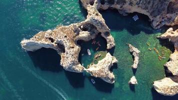 Luftdrohnenaufnahme von Kajaks und Booten, die um die magischen Kalksteinfelsen von Ponta da Piedade herumfahren. erforschung der höhlen und tunnel von lagos, algarve, südlich von portugal. Reisen und Abenteuer. Nomadenleben. video