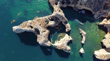 Luftdrohnenaufnahme von Kajaks und Booten, die um die magischen Kalksteinfelsen von Ponta da Piedade herumfahren. erforschung der höhlen und tunnel von lagos, algarve, südlich von portugal. Reisen und Abenteuer. Nomadenleben. video