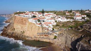Aerial drone view of a natural pool in the ocean, next to the cliff and a seaside village during a sunny day. Azenhas do Mar, Portugal. Summer holidays and travel. Enjoying life. Vibrant colors. video