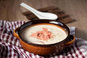 cheese soup with vegetables and ham with toast close-up on the table. horizontal sprinkle oregano in brown bowl. photo