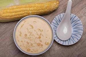 sopa de maíz dulce en una taza de cerámica sobre fondo de madera. foto