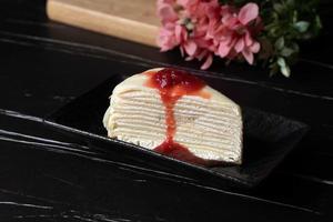 Strawberry crepe cake layered in black tones. photo