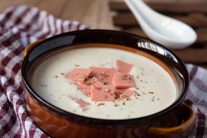 cheese soup with vegetables and ham with toast close-up on the table. horizontal sprinkle oregano in brown bowl. photo