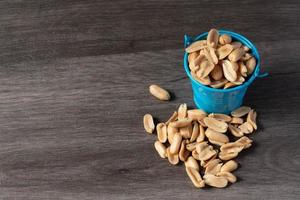 Baked peanuts in a bucket on a wooden background photo