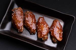 Fried chicken wings with spicy and sweet Korean sauce topped with white sesame seeds photo