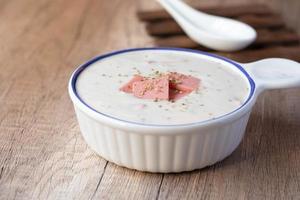 Cheese soup with vegetables and ham with toast on the table close-up horizontal sprinkle oregano in white bowl