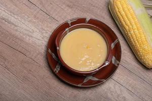 Sweet corn soup in a ceramic cup on wooden background. photo