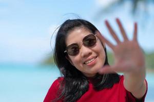 retrato de una mujer adulta madura asiática con gafas de sol con fondo oceánico foto