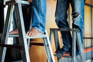 Selective focus on the aluminum ladder with defocused feet of workers working on it photo