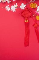 Design concept of Chinese lunar new year - Beautiful Chinese knot with plum blossom isolated on red background, flat lay, top view, overhead layout. photo