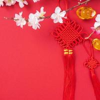 Design concept of Chinese lunar new year - Beautiful Chinese knot with plum blossom isolated on red background, flat lay, top view, overhead layout. photo