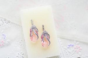 Crystal earrings on white fabric background photo