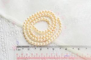 pearl necklace on white fabric background, Close up shot of glass pearls photo